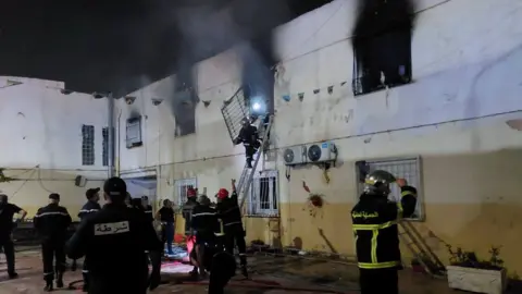 Reuters Rescuers and police officers work at the site of a fire at an orphanage near Algiers on 16 July.