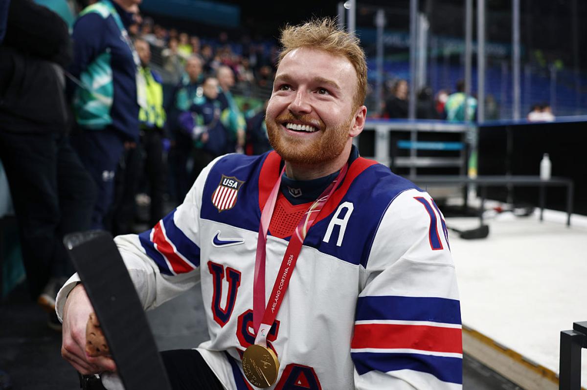 A USA Para ice hockey player smiling with his gold medal outside the rink in a packed arena